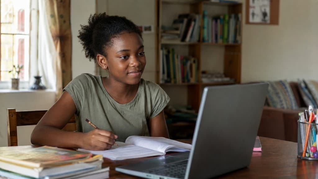 Student studying at a desk with a laptop and books